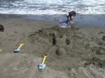 砂の彫刻「人間」に、波がせまっている。